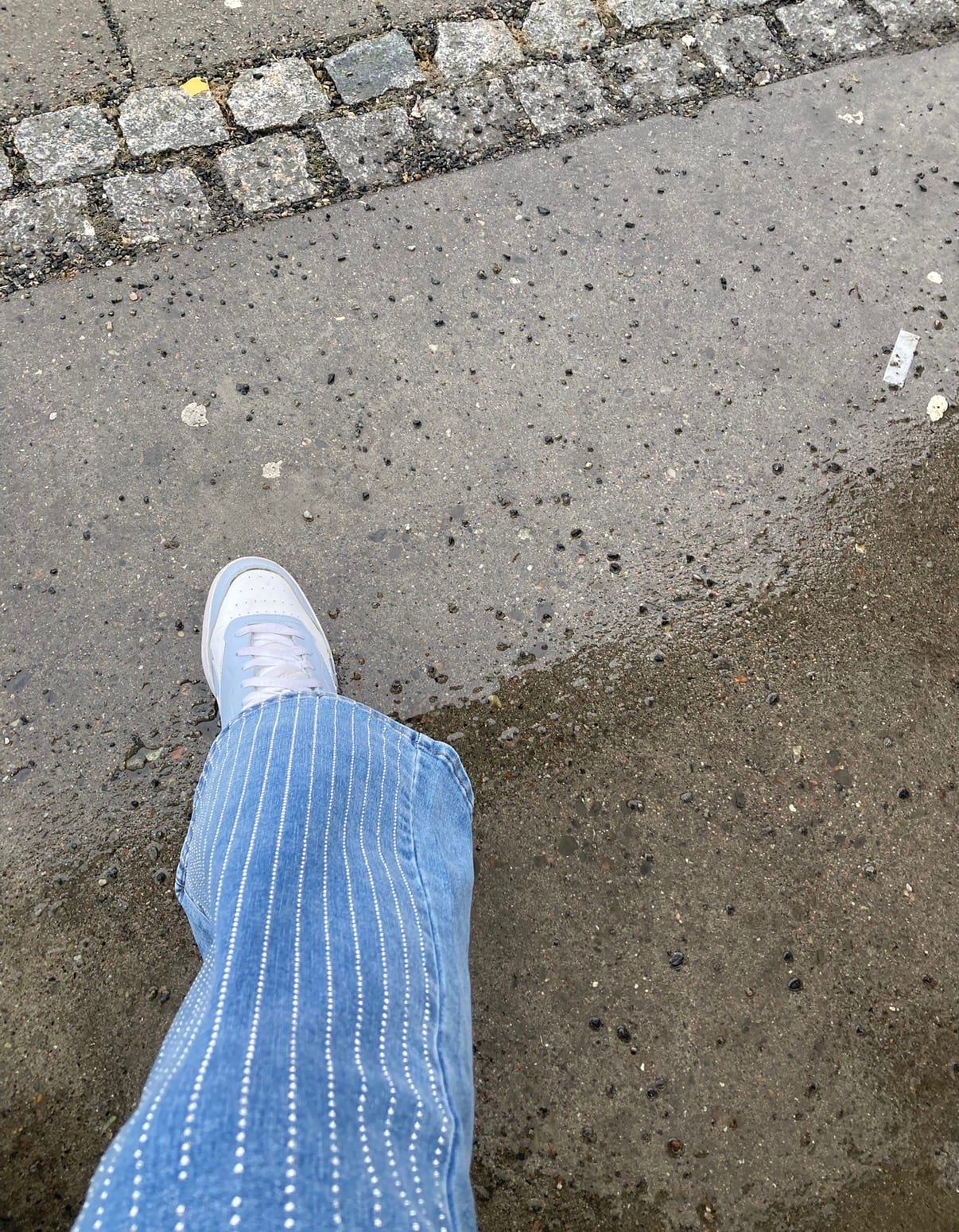 Detalj av lyseblå jeans med rhinsteiner og sneakers