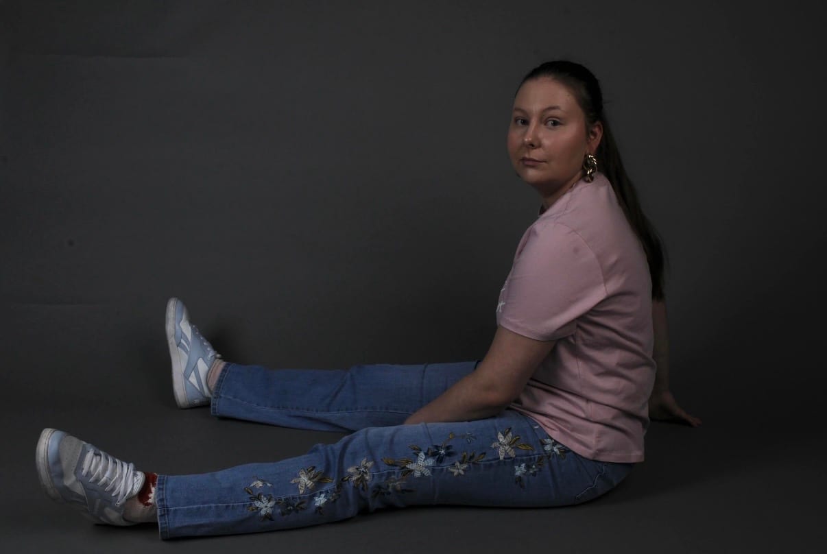 NOVIA i rosa topp og brodert jeans foran mørk bakgrunn